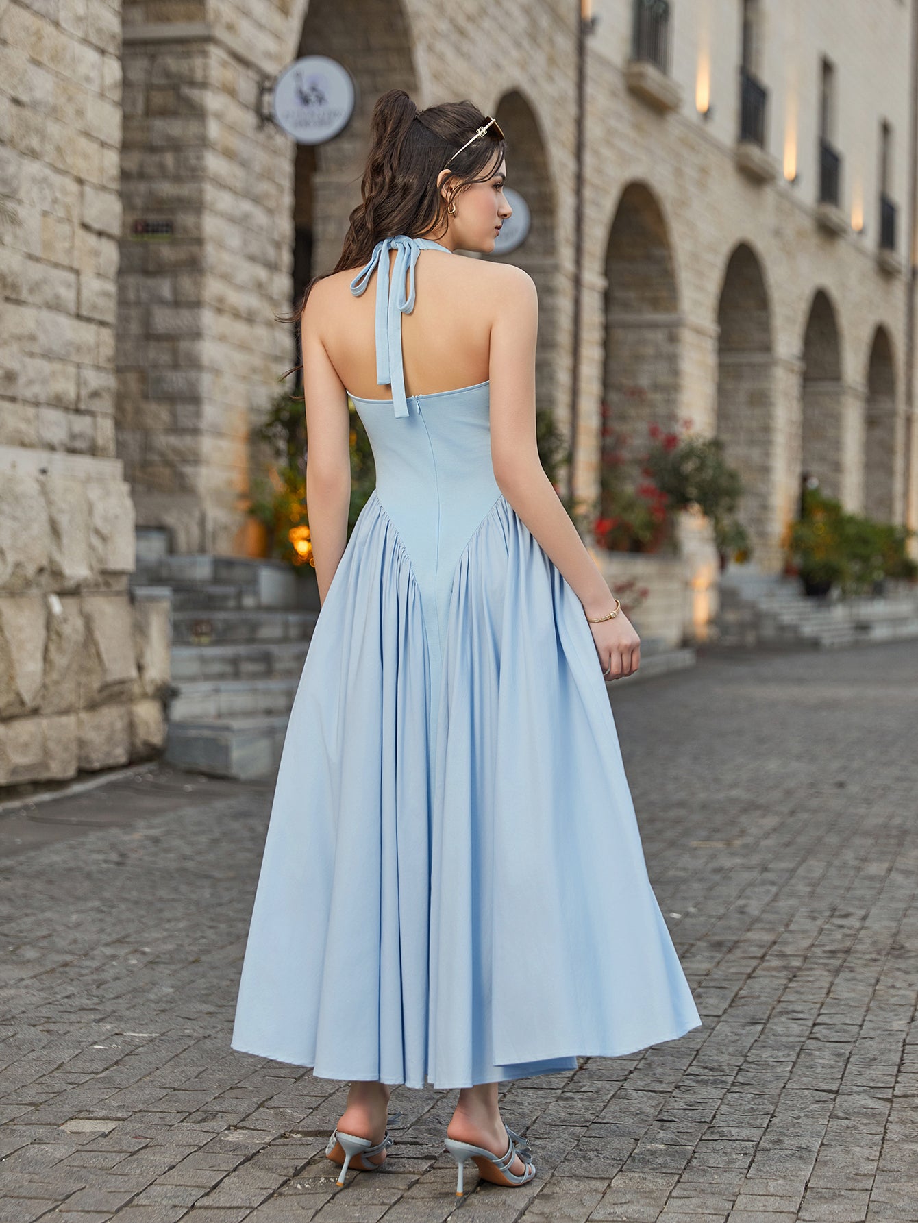 Back view of a woman in a light blue halter neck midi dress