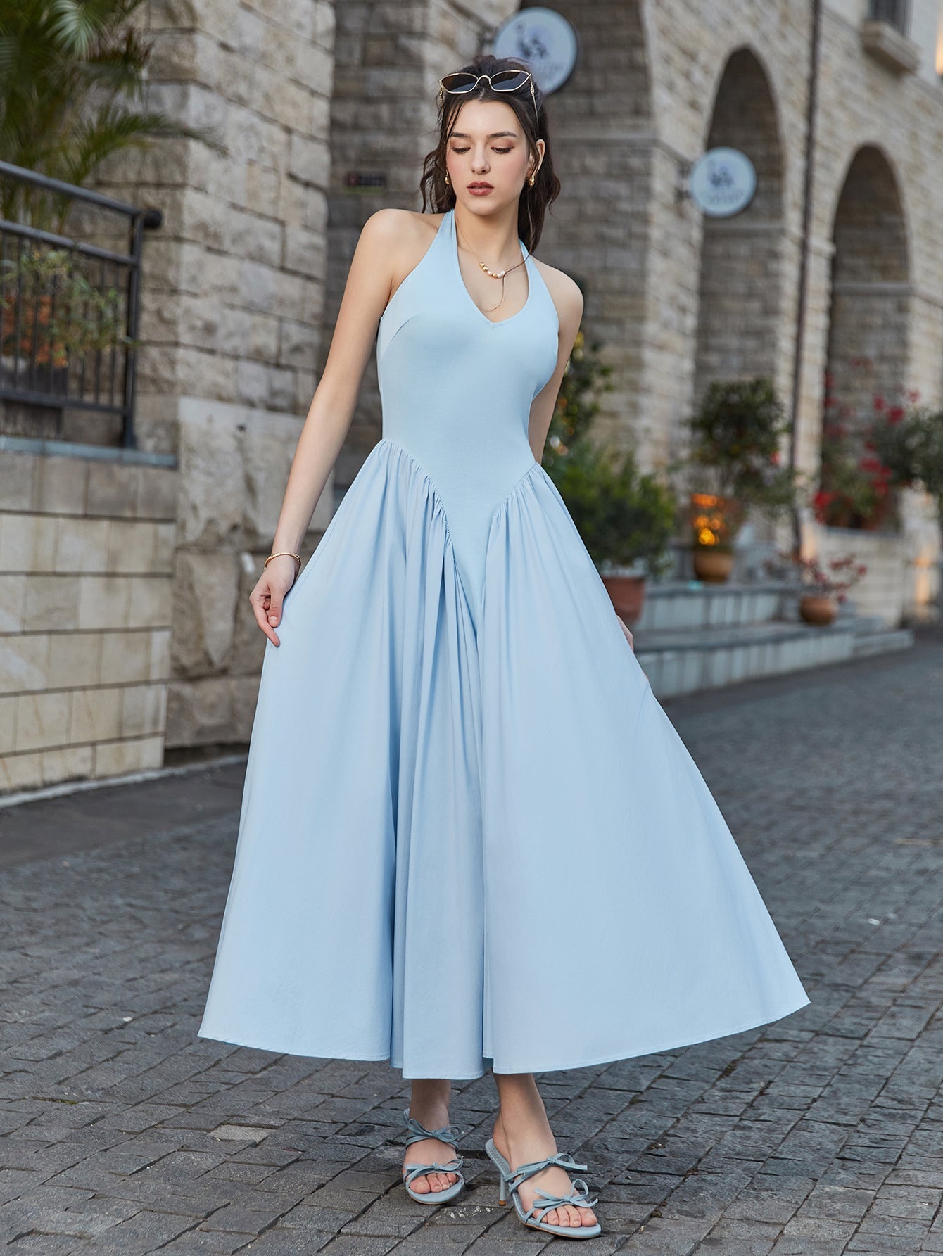 Woman showcasing the flowy skirt of a light blue halter neck midi dress