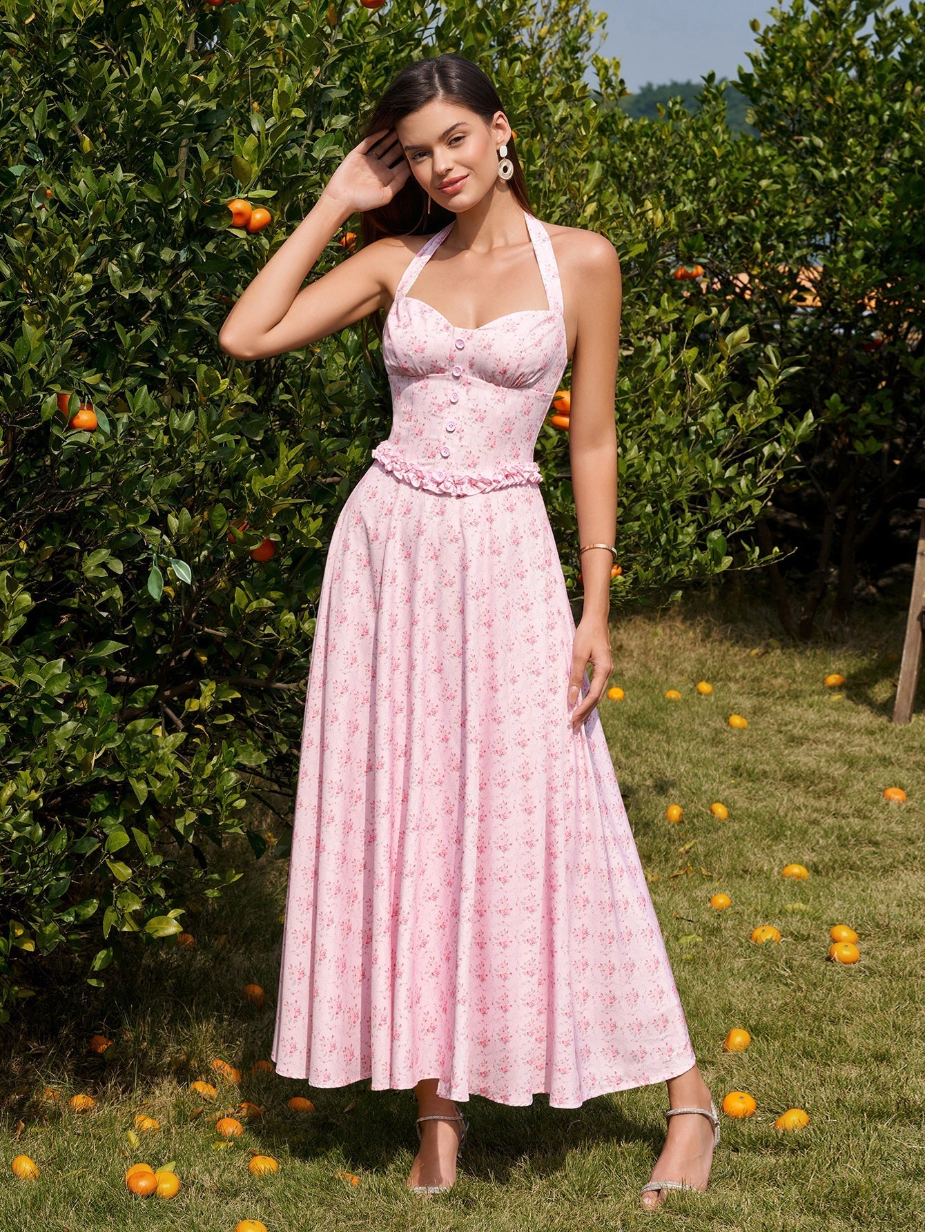 Woman wearing a pink floral print halter neck midi dress with a fitted bodice and A-line skirt.