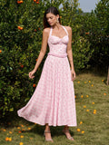 Woman twirling in a pink floral print halter neck midi dress, showcasing the flowing A-line skirt.