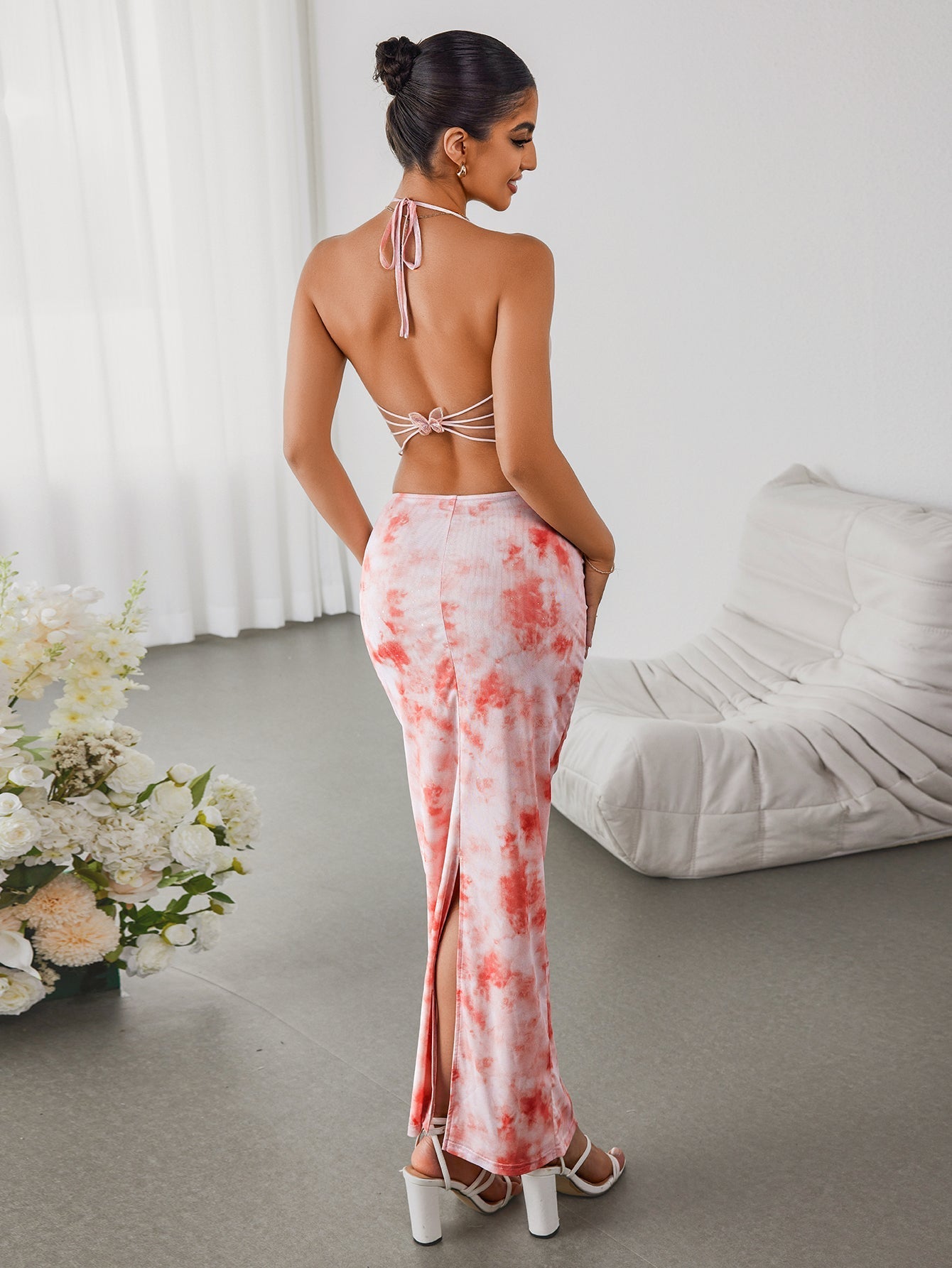 Woman from the back in a pink tie-dye halter maxi dress with a high slit