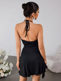 Back view of a woman in a black halter neck mini dress with an open back