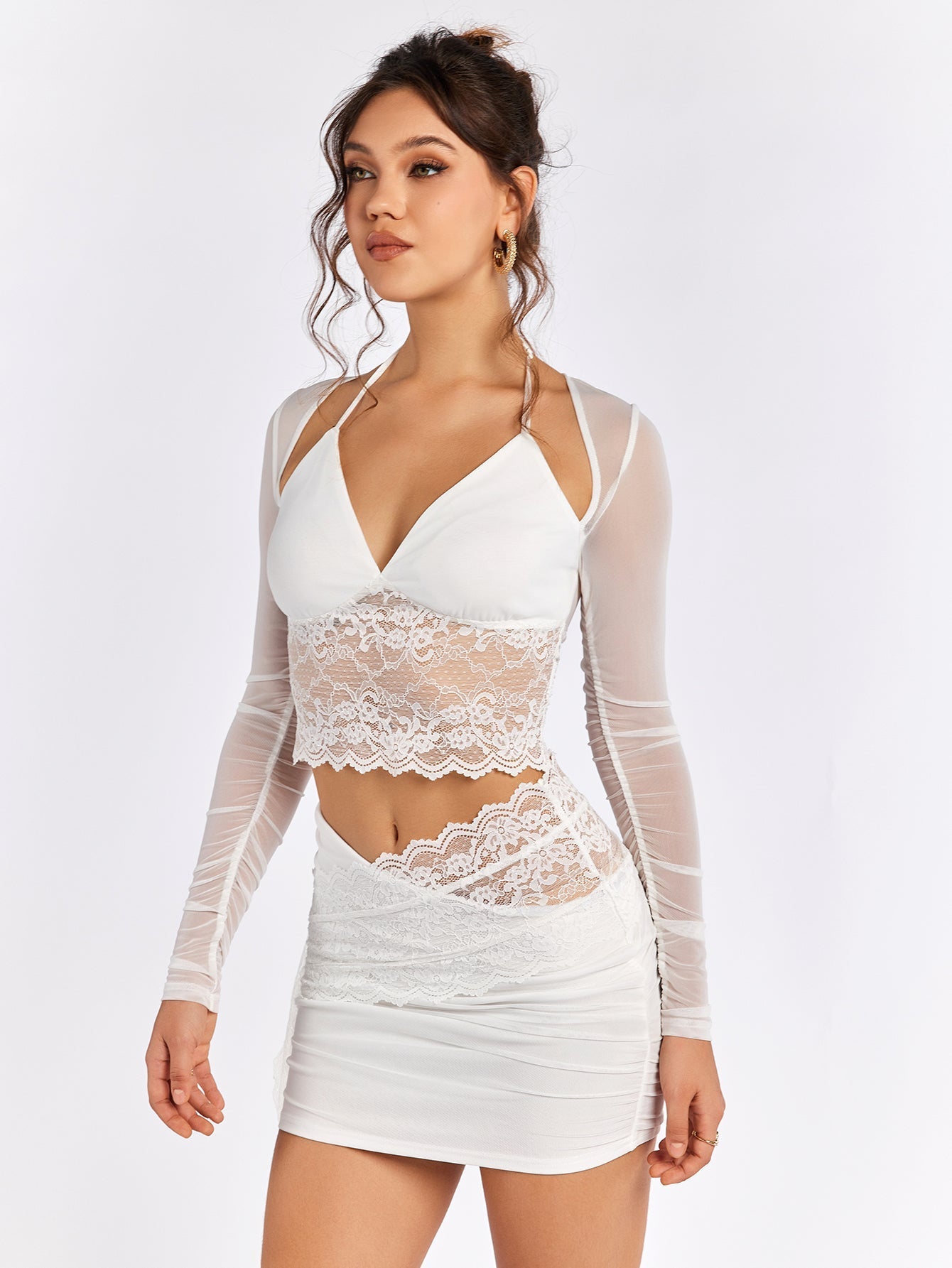 Woman posing in a white lace and mesh top with a ruched skirt.