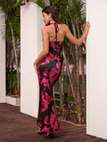 Back view of a woman in a black and pink floral print halter maxi dress with a cut-out detail.