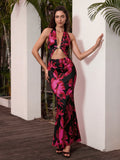 Woman wearing a black and pink floral print halter maxi dress with a cut-out detail and gold hardware.