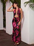 Woman posing in a black and pink floral print halter maxi dress with a cut-out detail and gold hardware.