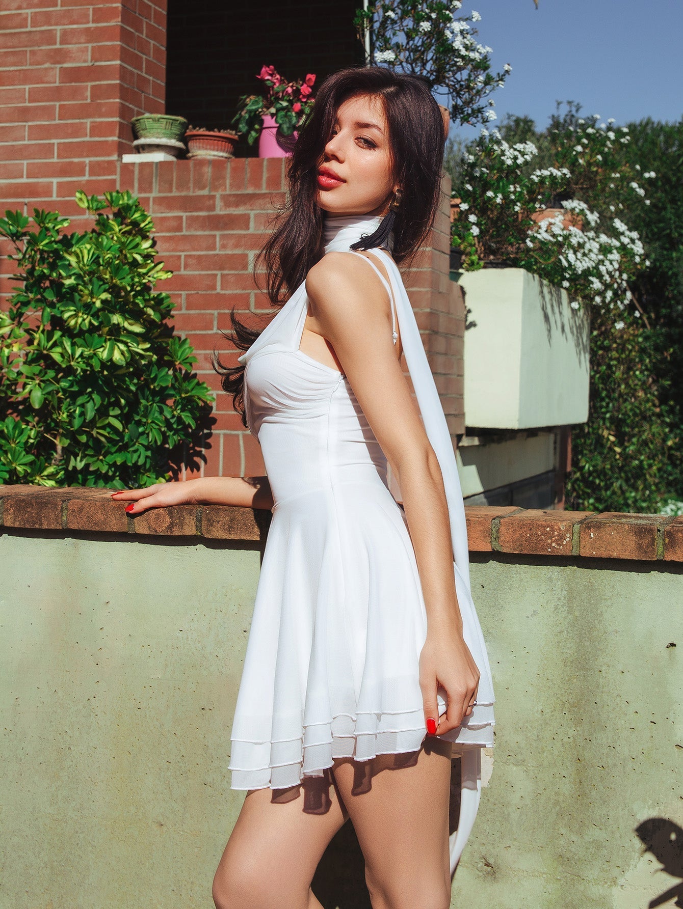 Side profile of woman in white dress with flowing scarf detail