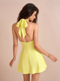 Back view of a woman in a yellow halter neck dress with a bow detail