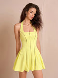 Close-up of a woman in a yellow halter neck dress with a square neckline and cutout details