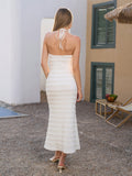 Back view of a woman in a white halter neck midi dress with a textured fabric