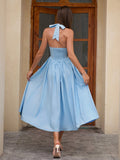 Back view of a woman in a light blue halter neck midi dress with a smocked back and tie closure.