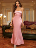 Full length shot of a woman in a pink satin trumpet dress with a halter neckline.
