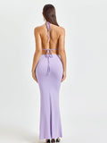Back view of a woman in a lavender backless halter crop top and mermaid maxi skirt