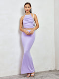 Full-length shot of a woman in a lavender ruched halter crop top and mermaid maxi skirt, holding a white handbag