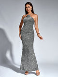 Woman modeling a silver sequined halter neck mermaid gown, looking at camera