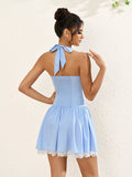 back view of a woman in a light blue halter neck dress with smocked back and lace trim