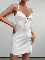 Front detail of a white satin mini dress with a halter neckline and tie front