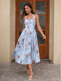 Woman twirling in a light blue floral print halter neck midi dress with a flared skirt in front of a doorway.