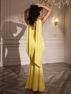 Back view of a woman in a strapless yellow mermaid gown with a scarf accent.