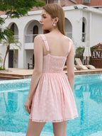 Back view of a woman in a pink textured floral mini dress with a smocked back panel and adjustable straps.