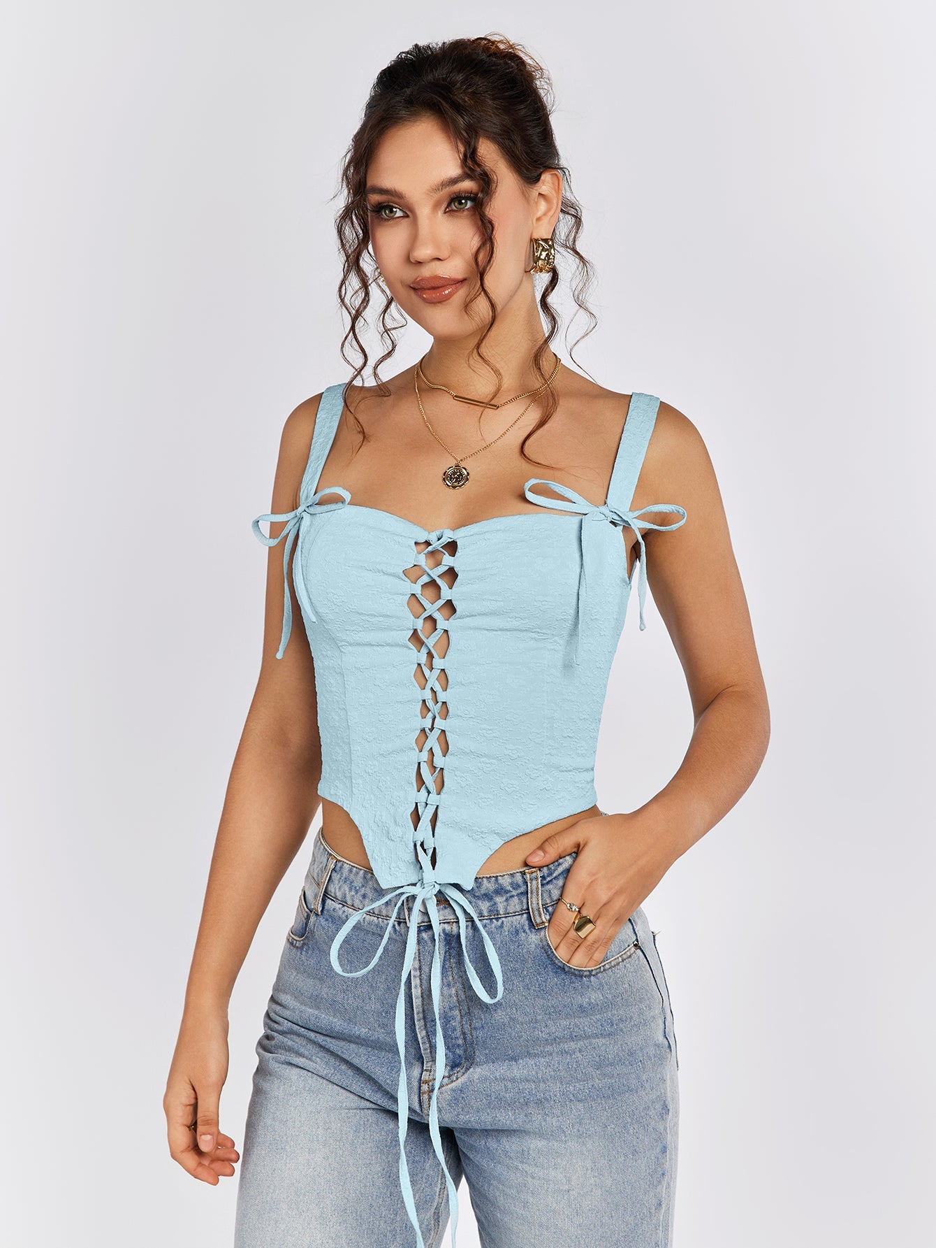 Woman in a light blue jacquard lace-up camisole, hand in pocket