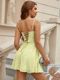Back view of a woman in a yellow lace mini dress with a criss-cross lace-up back detail.