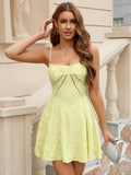 Woman in a yellow lace mini dress with spaghetti straps and cut-out details on the bodice, touching her hair.
