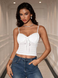 Woman in a white cropped camisole top and blue jeans, with hands in pockets.
