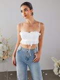 Woman in a white cropped top and blue jeans, looking to the side