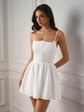 Model posing in a white textured mini dress with scalloped trim detail.