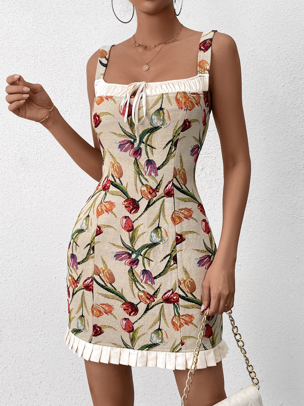 Woman holding a chain strap handbag while wearing a floral print dress