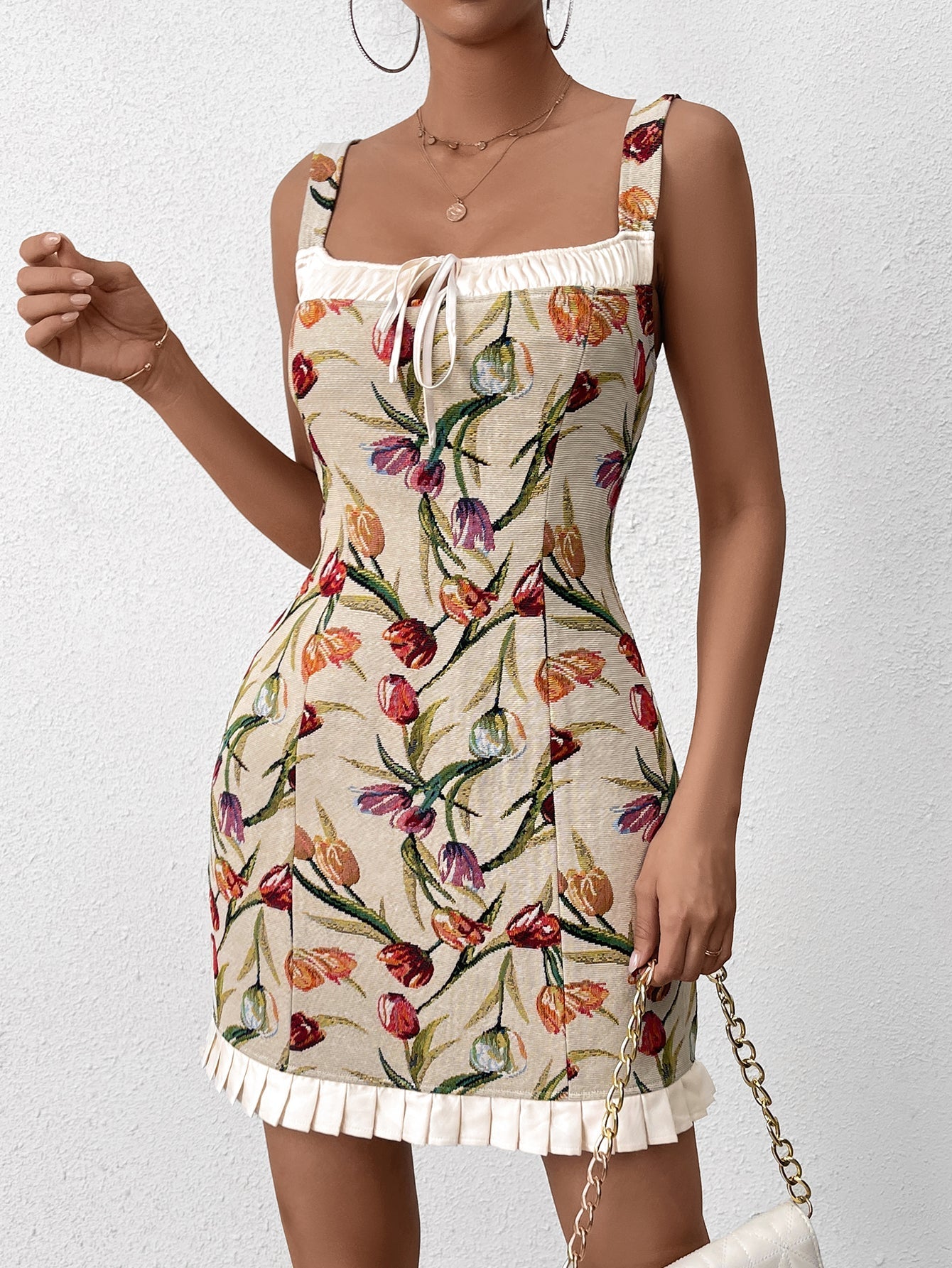 Woman holding a chain strap handbag while wearing a floral print dress
