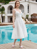 Front view of a woman in a white eyelet embroidered midi dress, posing by a swimming pool.
