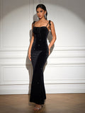 Woman wearing a black velvet evening gown with a ruched bust and mermaid hem