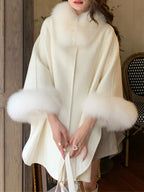 Woman wearing a cream-colored wool blend cape with fur trim collar and cuffs.
