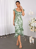 Woman in a green floral print mermaid dress with ruffled neckline and tiered hem