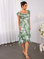 Woman posing in a green floral print mermaid dress with ruffled neckline and tiered hem