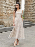 Woman wearing a cream floral print midi dress with a tie-front bodice and lace trim