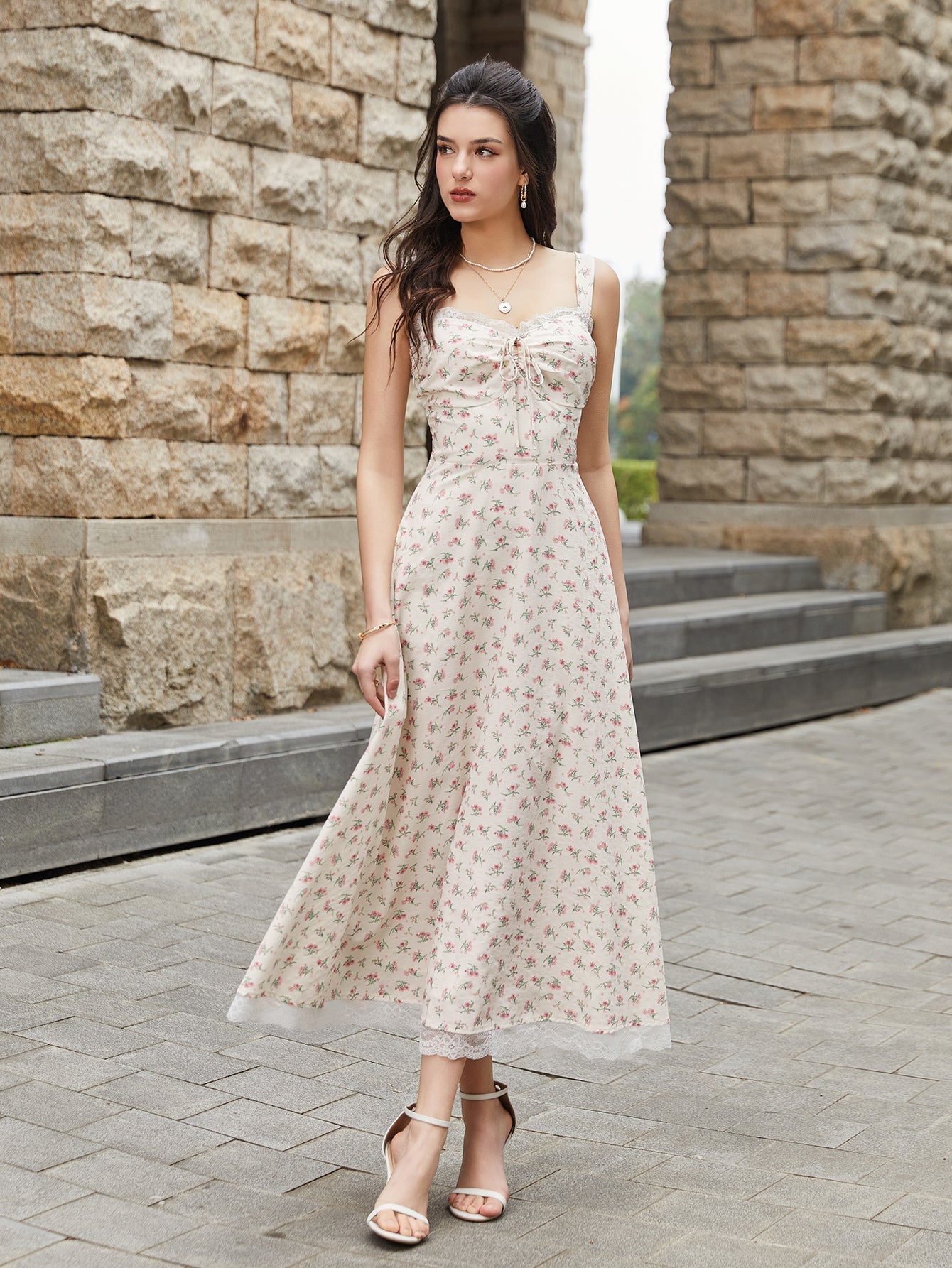 Woman wearing a cream floral print midi dress with a tie-front bodice and lace trim