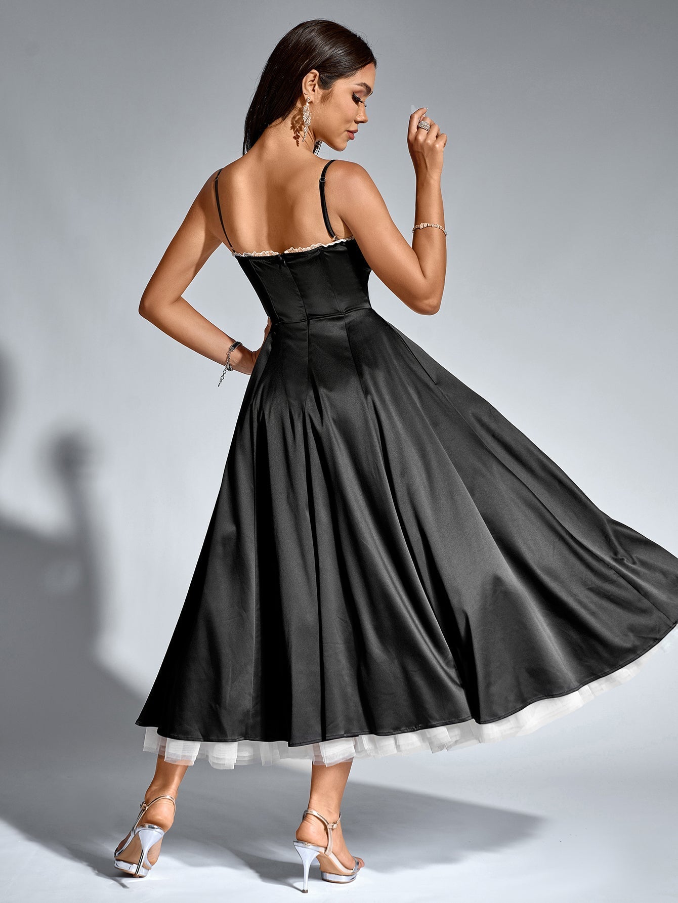 Back view of a woman in a black satin fit and flare midi dress.