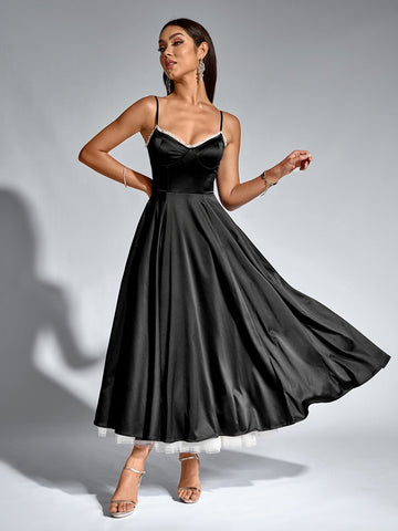 Woman in a black satin fit and flare midi dress with spaghetti straps and lace trim.