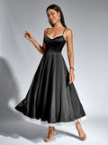 Woman smiling and twirling in a black satin fit and flare midi dress.