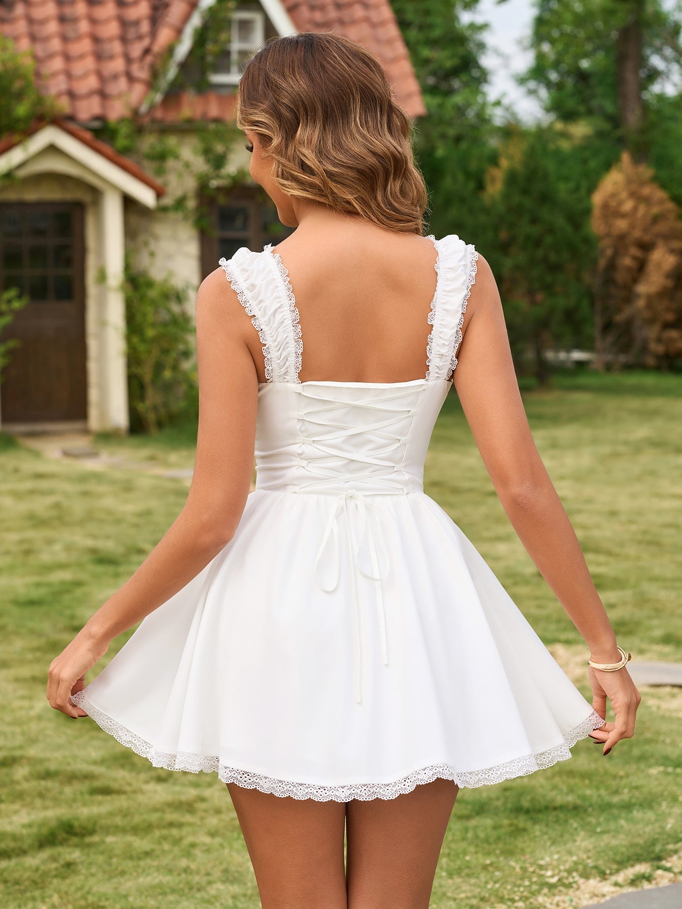 Back view of a woman in a white mini dress with a corset back and lace trim.