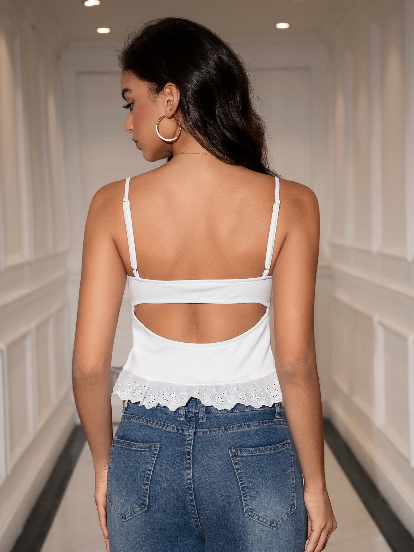 Back view of a woman in a white cropped tank top with an open back detail
