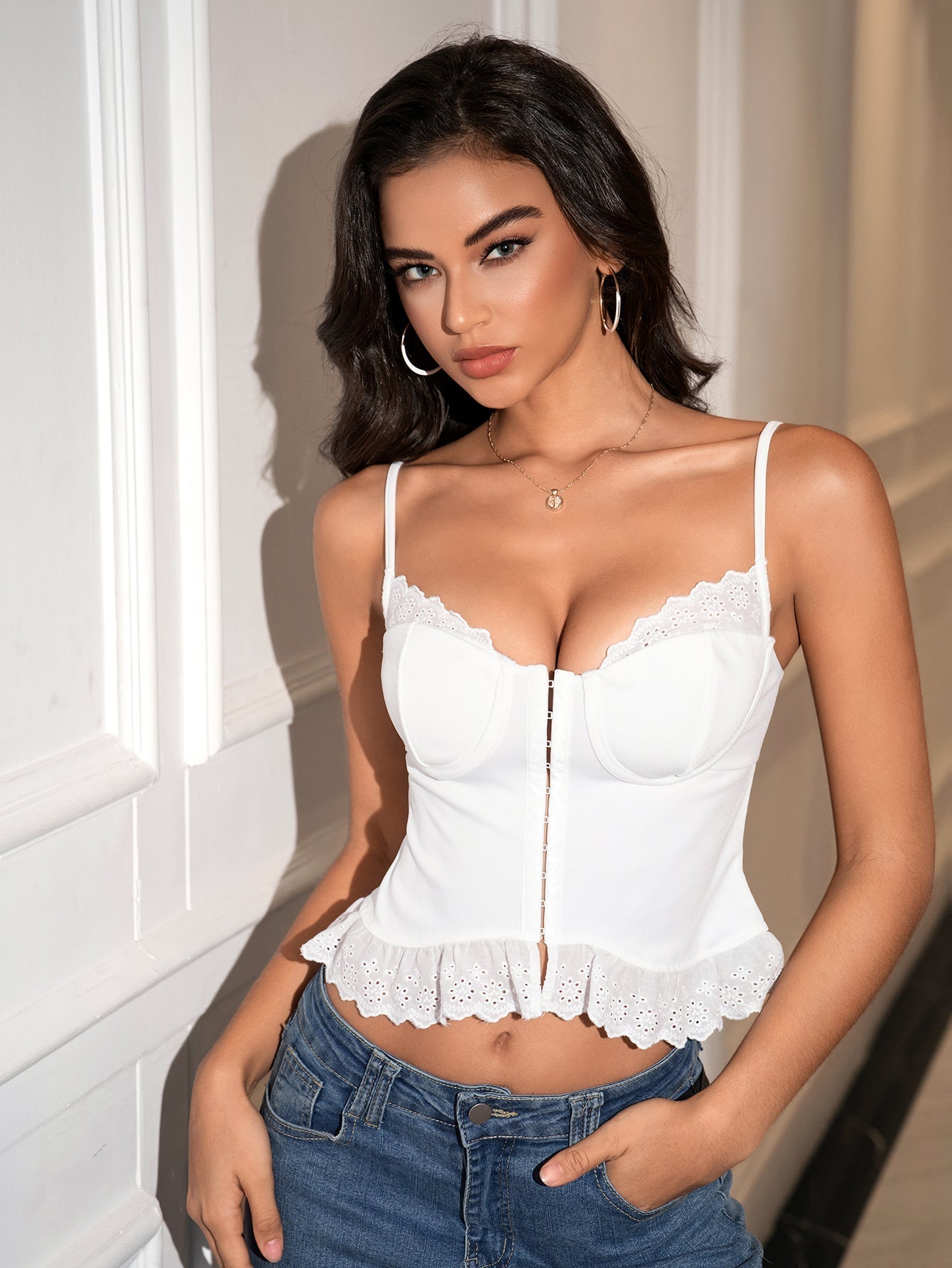 Woman posing in a white cropped tank top and blue jeans