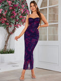 A woman poses in a floral print evening gown with delicate spaghetti straps.