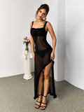 Woman wearing a long black sheer dress with ruffled trim in a studio setting