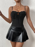 Woman wearing a black ribbed knit camisole with lace trim and a tie-front detail.