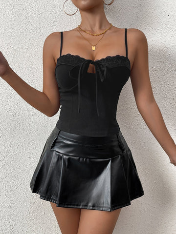 Woman wearing a black ribbed knit camisole with lace trim and a tie-front detail.