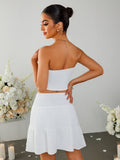 Rear view of a woman in a white strapless cropped top and a white tiered mini skirt with a smocked waistband.